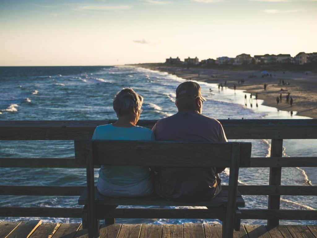 Elderly couple sitting by ocean
