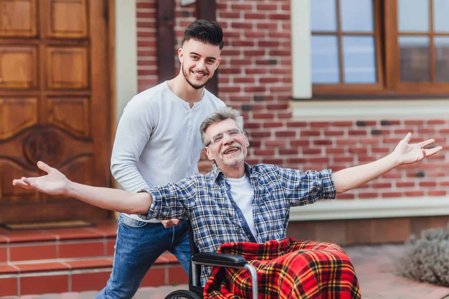 Senior father in wheelchair and young son on a walk.